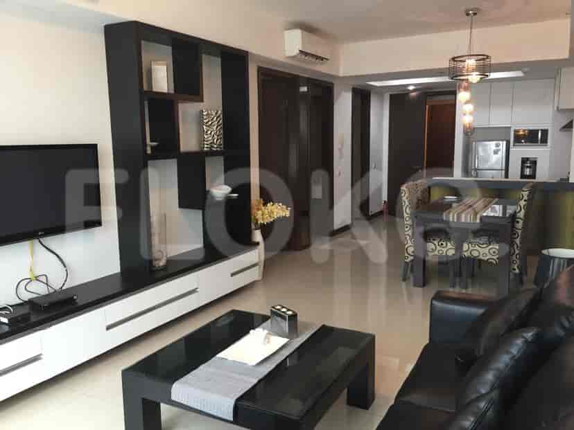 A modern living room with a black sofa, a dining table, and an open kitchen.