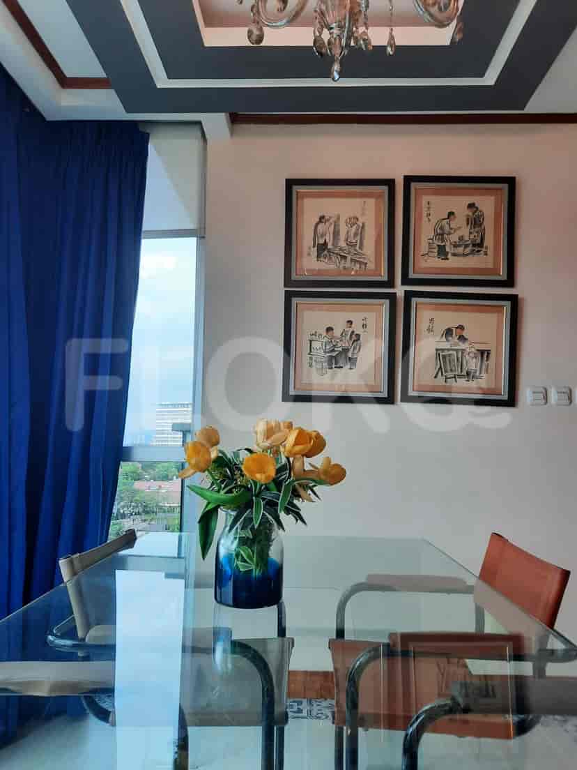Dining area with a glass table, chairs, and artwork.