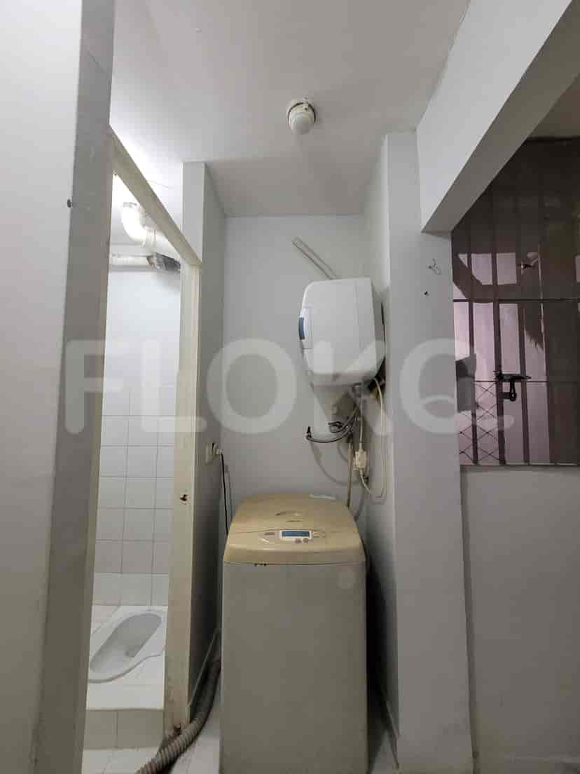 Kamar mandi kecil dengan toilet bergaya Barat, ubin putih, dan jendela kecil.
