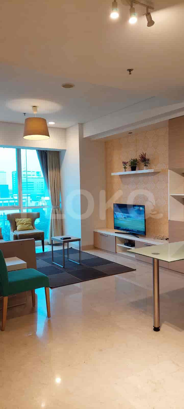 A modern living room with a TV, seating, and a large window.