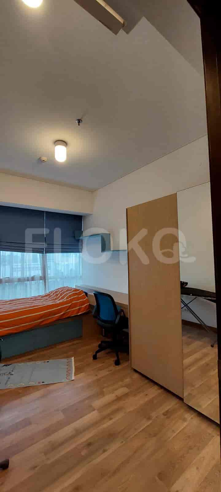 A bedroom with a bed, study desk, and wooden flooring.
