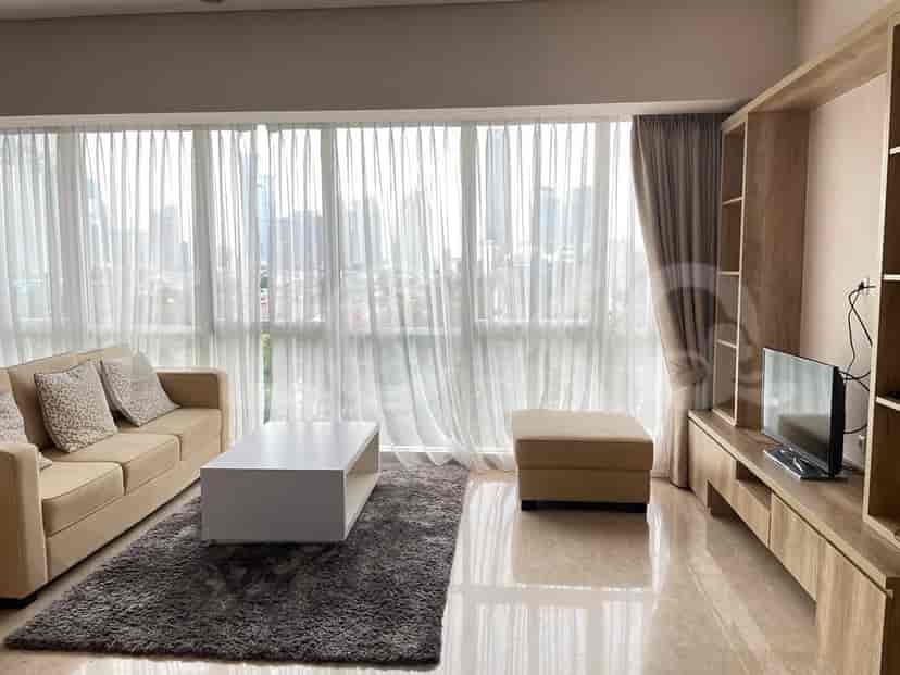 A bright living room with a sofa, coffee table, and floor-to-ceiling windows with a city view.
