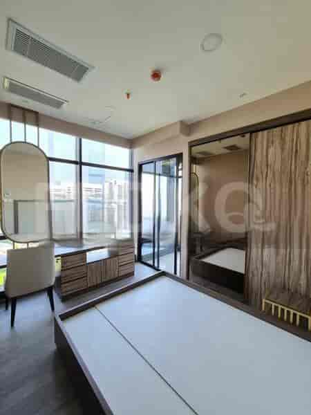A bedroom with a bed, large mirror, and wooden wardrobe.
