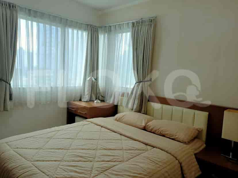 A bedroom with a double bed, desk, and large windows.