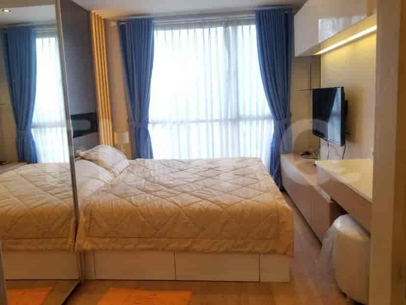 A bedroom with a bed, side tables, and large windows with blue curtains.