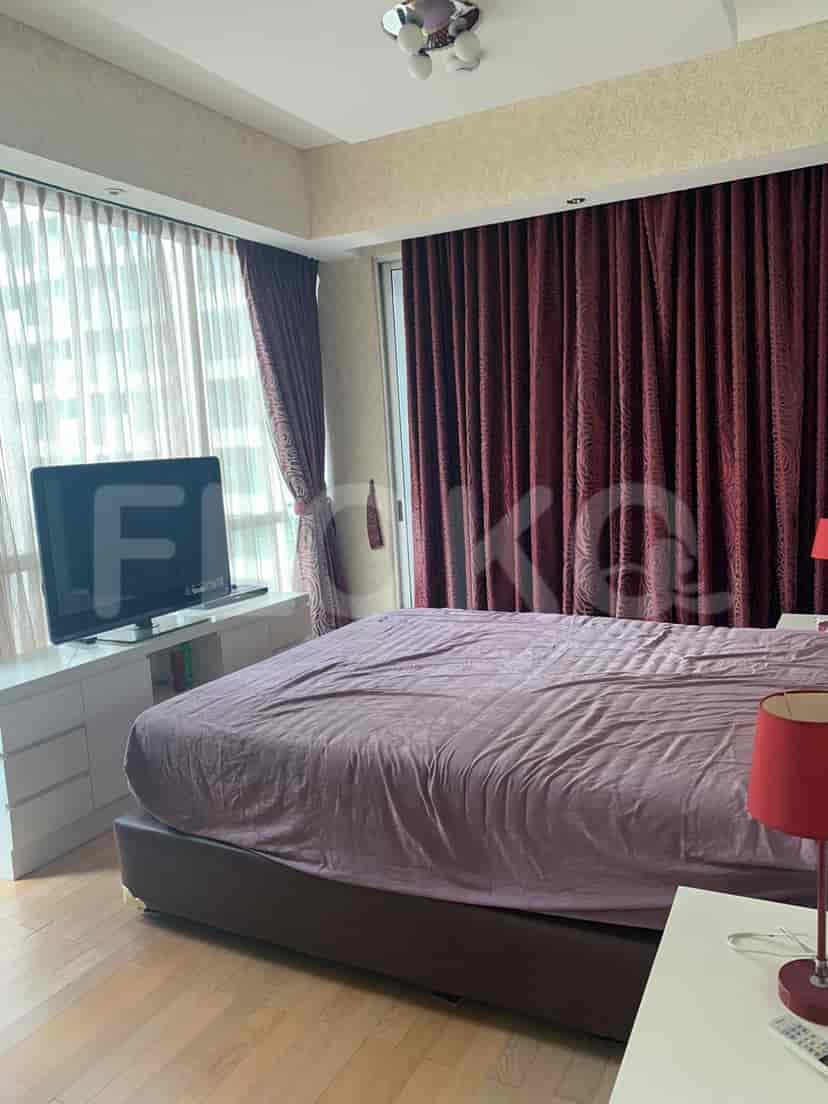 A bedroom with a bed, curtains, a TV, and a nightstand.