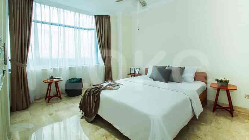 Kamar tidur dengan tempat tidur, meja samping, dan jendela besar.