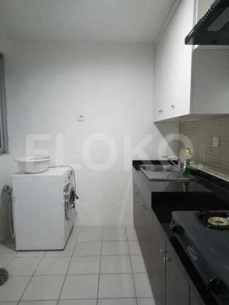 A compact kitchen featuring a washing machine, black countertops, and white cabinetry.