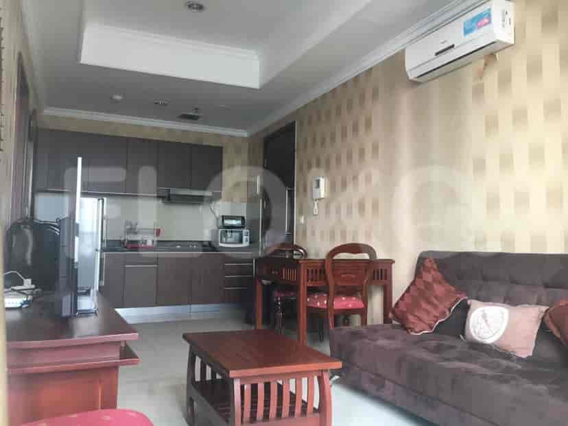 A combined living room and kitchen area featuring a sofa, dining set, and kitchen with built-in appliances.