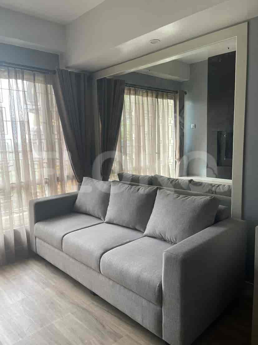 Living room with a grey sofa, large mirror, and sheer curtains.