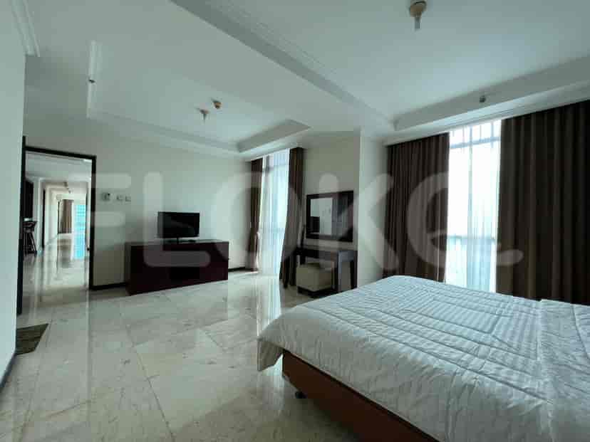 A well-lit bedroom with a bed, TV, and large windows.