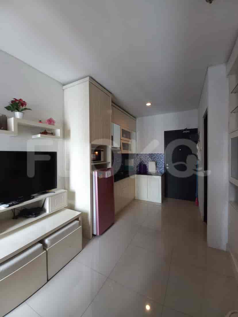 Living area and kitchen, with a television, cabinets and a small cooking space.