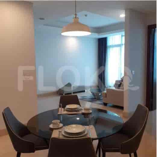 A dining area with a round glass table and four chairs under a pendant light.
