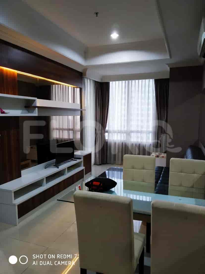 Ruang tamu yang terang benderang dengan area makan, unit hiburan, dan akses ke kamar tidur.
