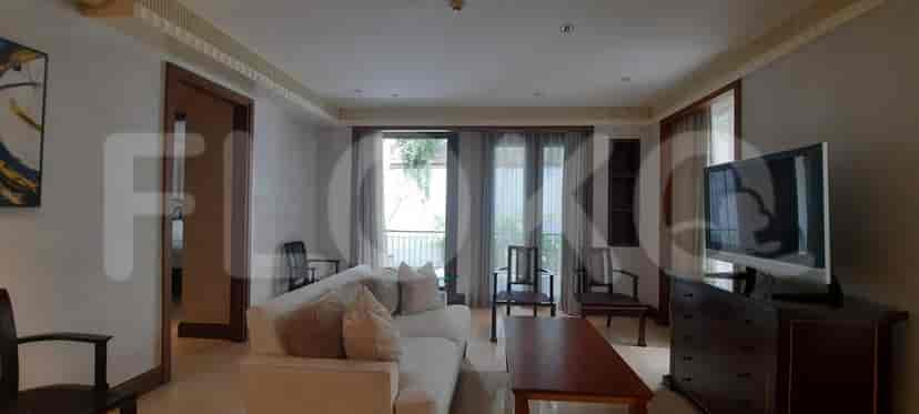 Ruang tamu dengan sofa, TV, dan akses balkon.