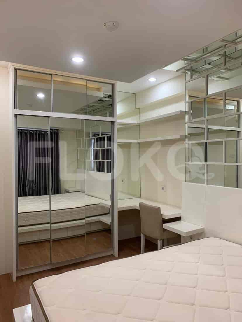 Kamar tidur dengan tempat tidur, lemari, dan meja, serta aksen dinding cermin.