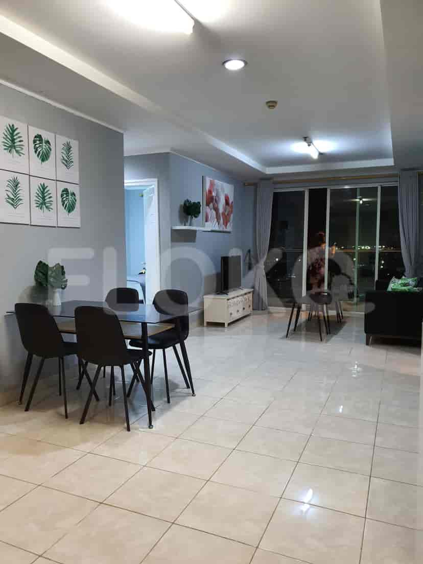 A combined living and dining space featuring a dining table, a sofa, and a large window.