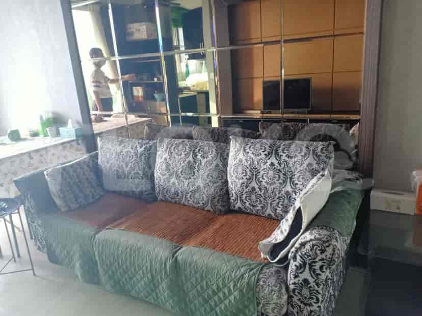 Living room with a patterned sofa, a mirrored wall, and a person in the background.