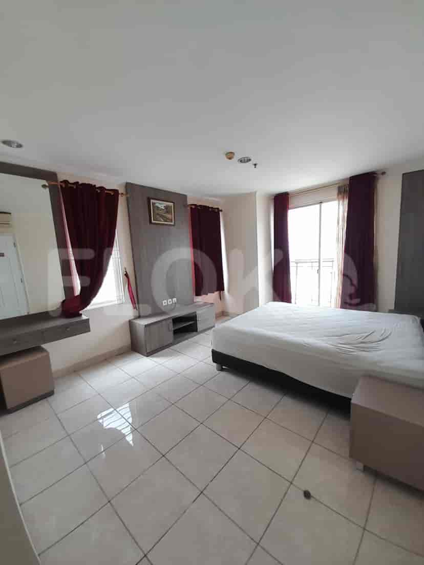 Kamar tidur utama yang luas dengan tempat tidur besar, gorden, dan lemari.