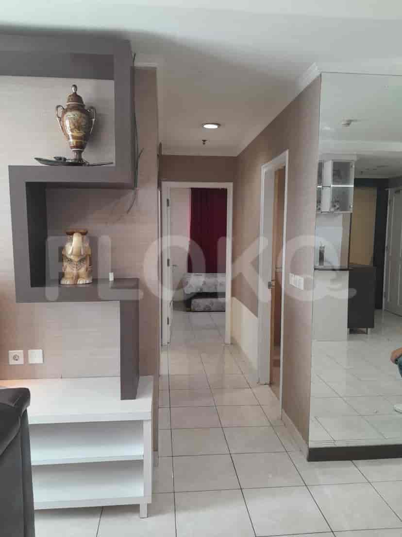 Pemandangan lorong, menampilkan ruang tamu, pintu kamar tidur, dan dekorasi.