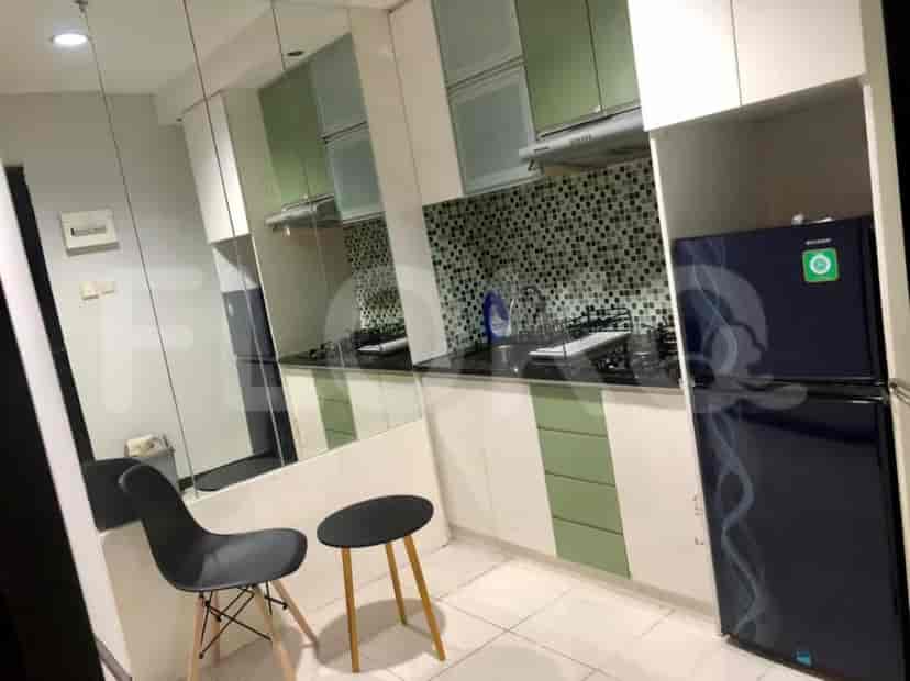 A well-equipped kitchen with green and white cabinets, a cooktop, and a refrigerator.