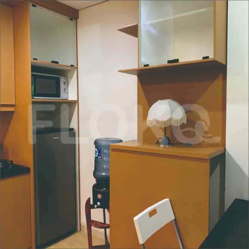 A modern kitchenette with wooden cabinets, a microwave, and a refrigerator.