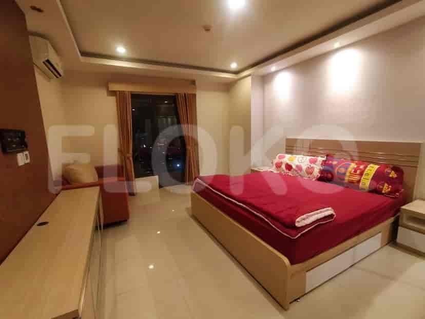 A bedroom with a double bed, nightstand, and a view of the city.