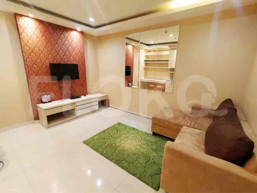 A modern living room featuring a green patterned rug, a plush sofa, and a wall-mounted TV.