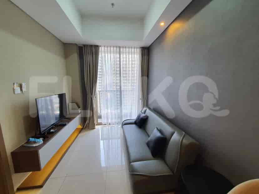 Modern living room with a grey sofa, wall-mounted TV, and large windows.