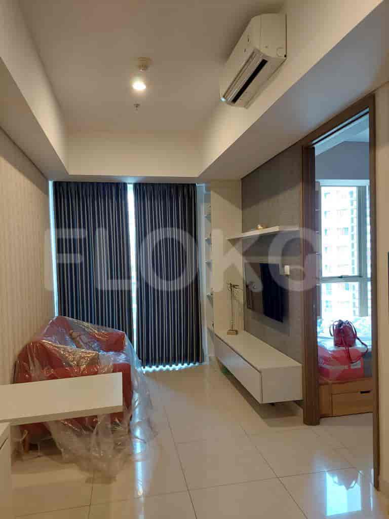 Living room with red chair covered in plastic, TV, and a window with curtains.