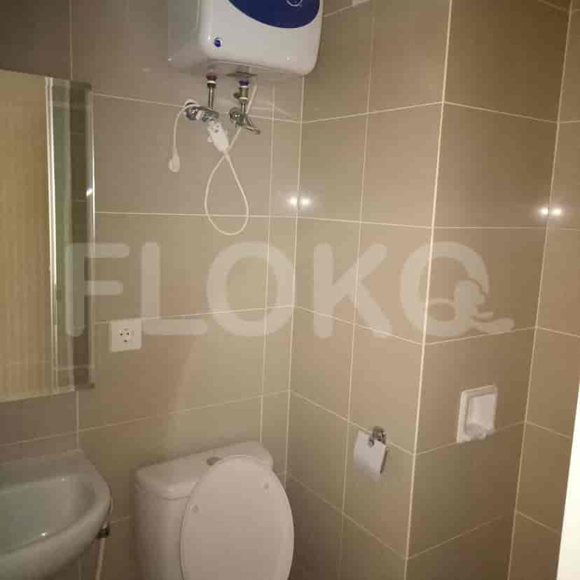 A bathroom with a toilet, sink, mirror, and an electric water heater.