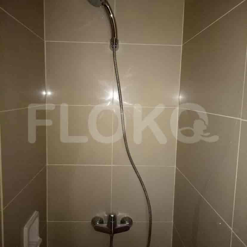 A shower with beige tiles, a hand-held showerhead, and a wall-mounted faucet.