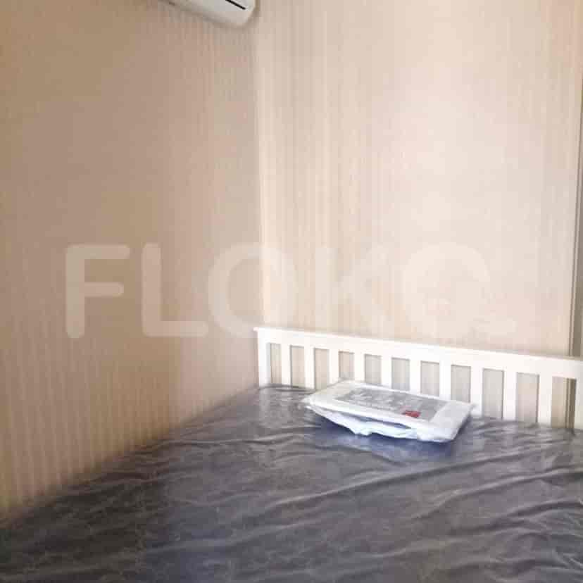 A bedroom featuring a bed with a white headboard, a package on the bed, and a view of the air conditioning unit.