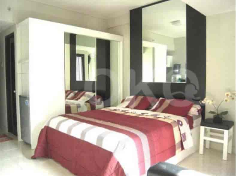 A bedroom showcasing a bed with red and white bedding, a mirrored closet, and a small side table.