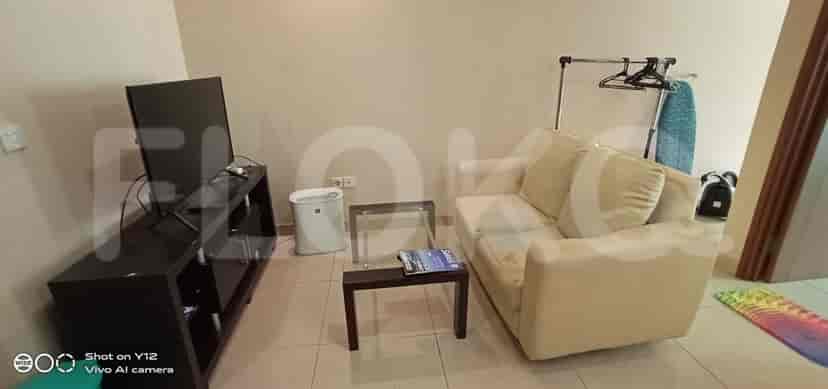 Ruang tamu dengan TV, sofa, dan meja kecil.