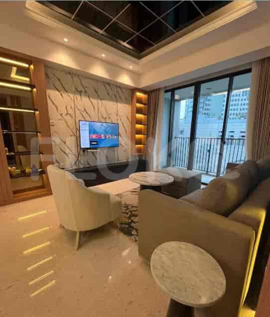 Ruang tamu yang luas dengan sofa abu-abu, dinding marmer, dan TV.