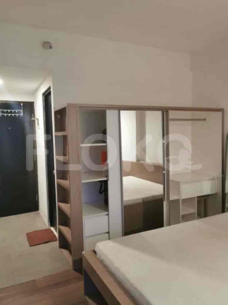 A studio apartment featuring a wardrobe with sliding doors and shelves, plus a bed.