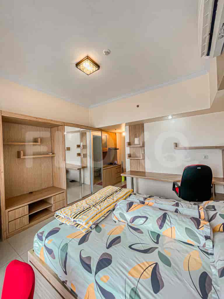 Sebuah kamar tidur dengan tempat tidur, lemari kayu, dan area meja.