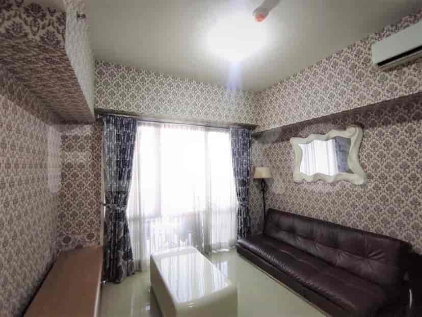 A living room with wallpaper, a brown leather sofa, and a large window.