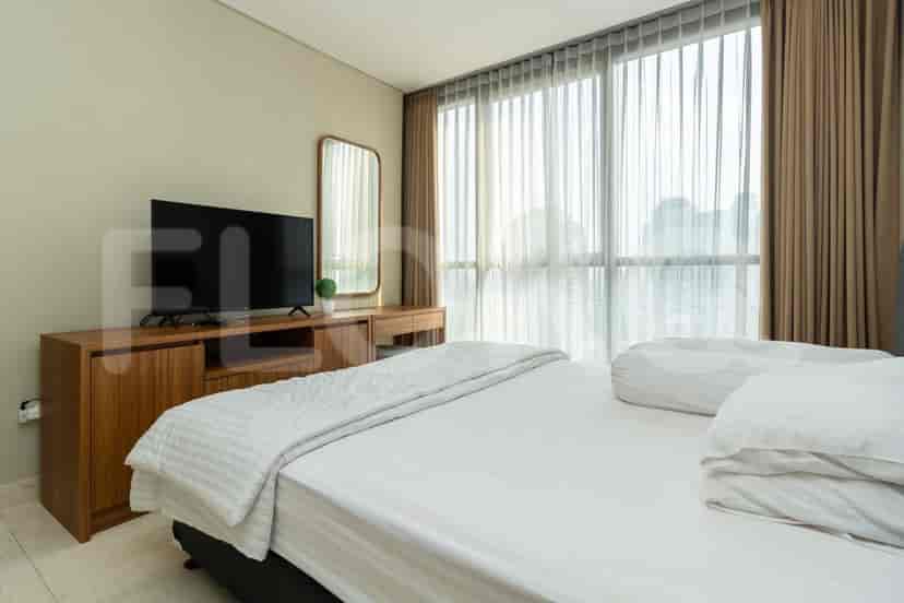 A bedroom with a bed, TV, mirror, and large windows.