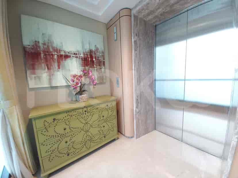 Area pintu masuk dengan karya seni, lift, dan lemari dekoratif, menampilkan perpaduan seni dan fungsionalitas.