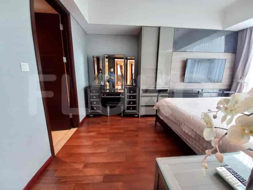 Kamar tidur utama yang menampilkan tempat tidur besar, lantai kayu gelap, dan area rias.