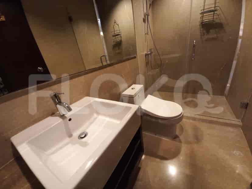 Kamar mandi modern dengan pancuran berkaca dan finishing marmer.