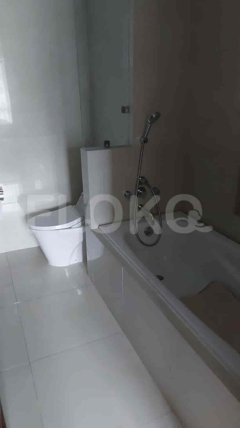 Kamar mandi yang bersih dengan bak mandi, toilet, dan pintu kaca shower.