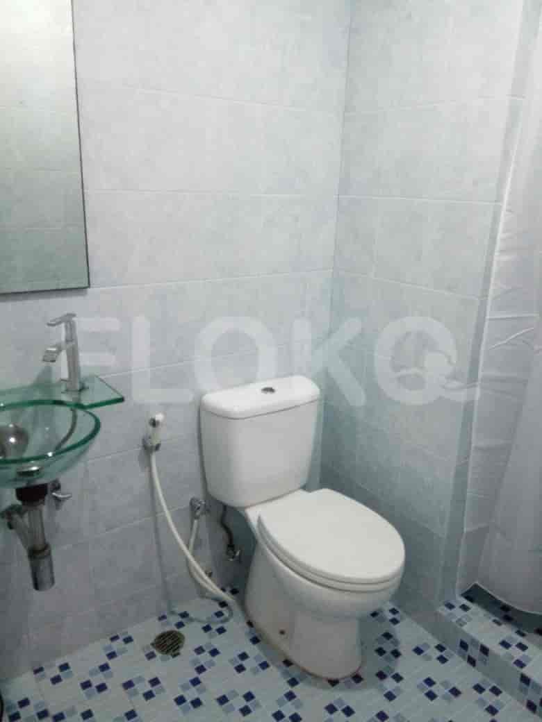A clean bathroom with light blue tiles, a modern sink, and a toilet.