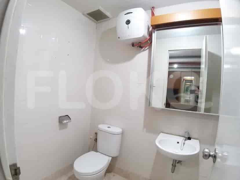 Kamar mandi yang ringkas dengan toilet, wastafel, dan pemanas air.