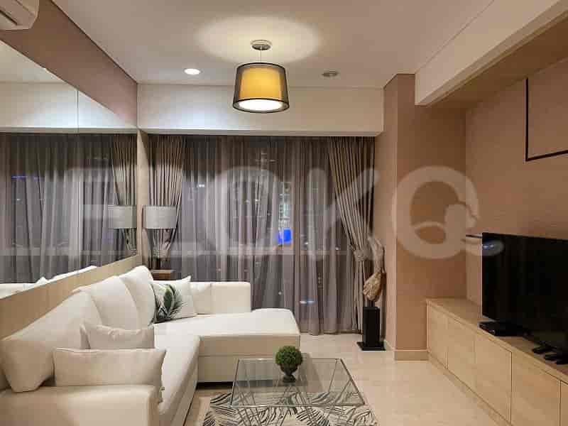 A modern living room with a white sofa, TV, and large windows.