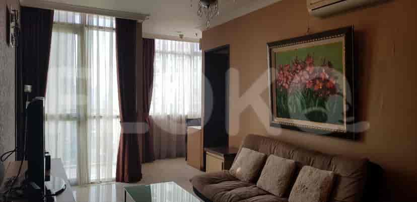A cozy living area with a brown sofa, a framed painting, and a large window.