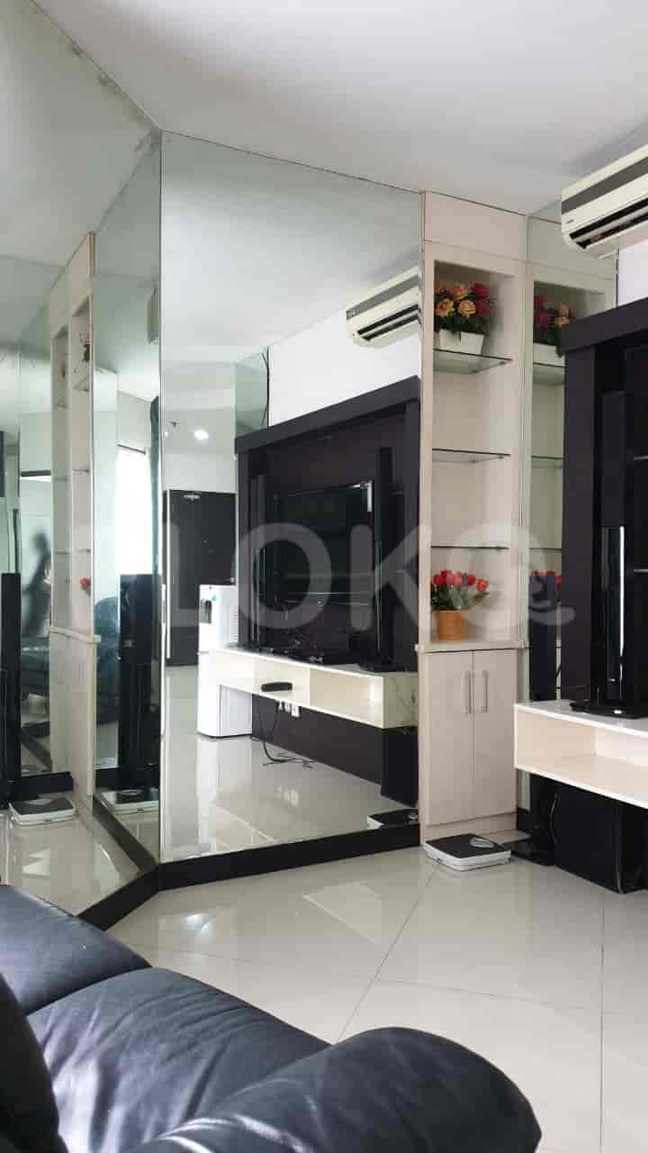 Spacious living room with a large wall-mounted TV, mirrored walls, and built-in cabinets.
