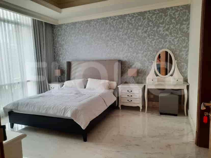 A spacious bedroom with a king-sized bed, vanity, and large windows.